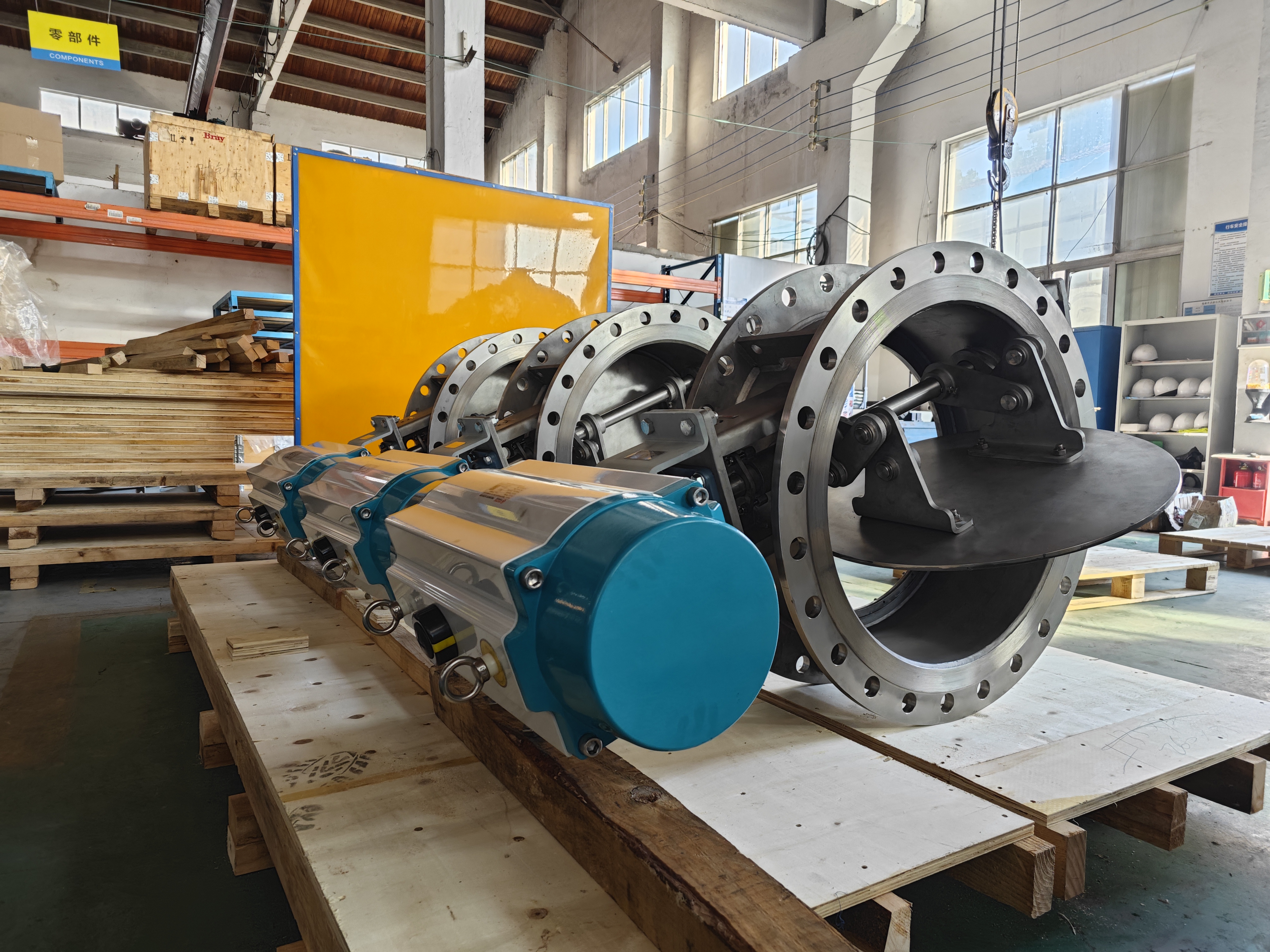 There are three finished stainless steel round flange pneumatic Offset Disk Dampers in the workshop equipped with pneumatic actuators used for exhaust isolation in the semiconductor industry