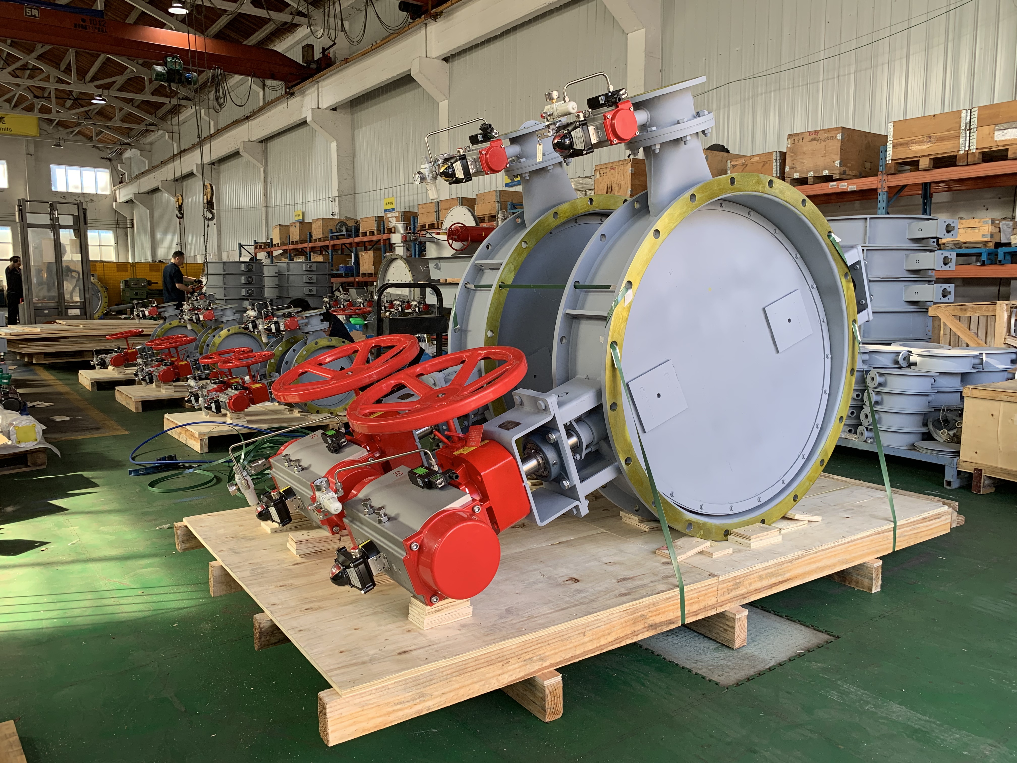 A round pneumatic air sealing isolation butterfly damper on a wooden pallet with a pneumatic actuator zero leakage used to cut off flue gas in boiler exhaust recirculation systems