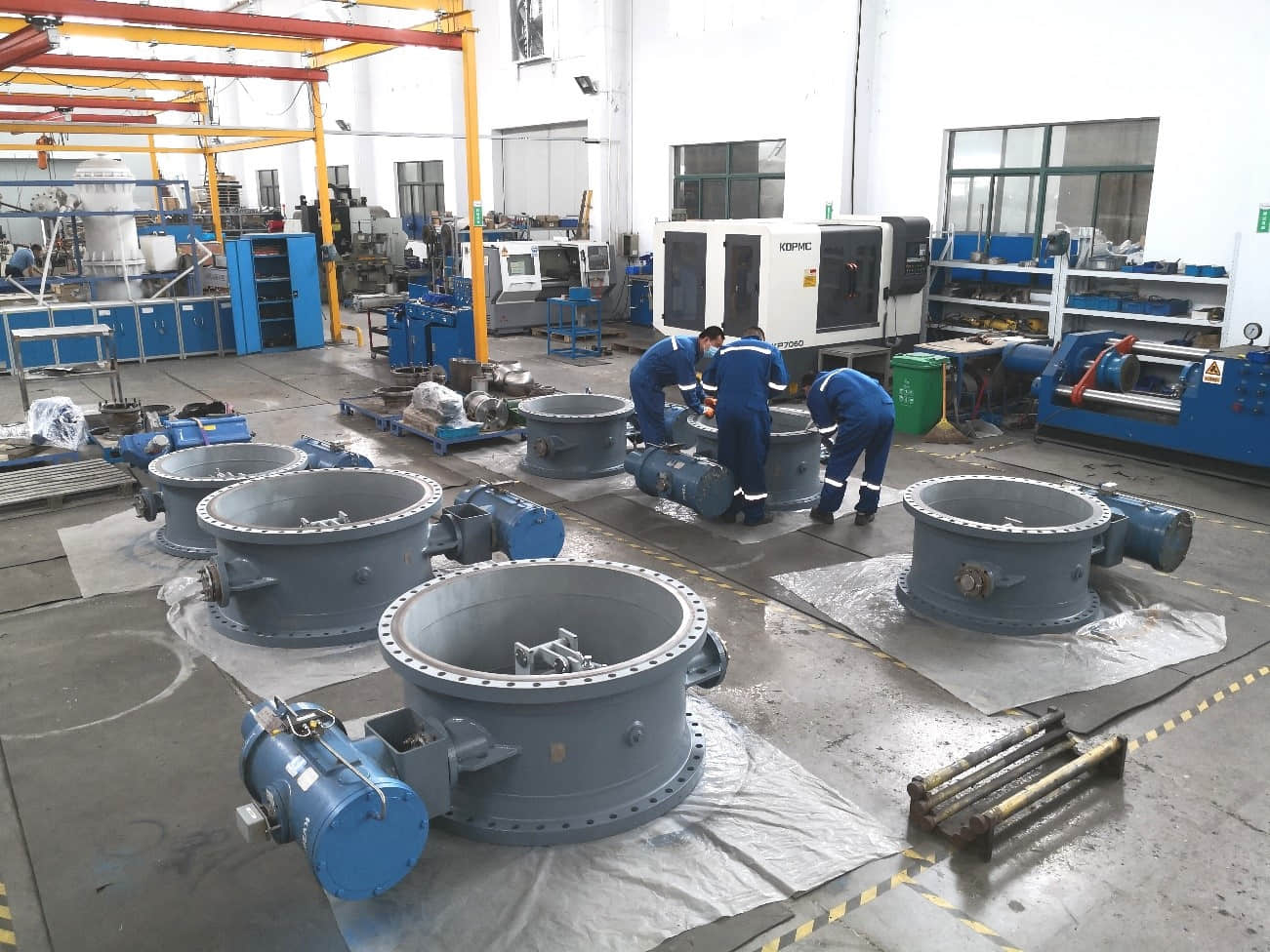 A batch of large-diameter pneumatic flue butterfly dampers undergoing workshop service.